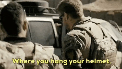 a man in a military uniform is talking to another man in a jeep .