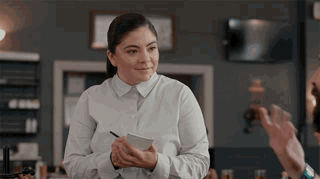 a woman in a white shirt is taking a order from a man