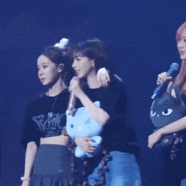 two women are standing next to each other on a stage holding a microphone .