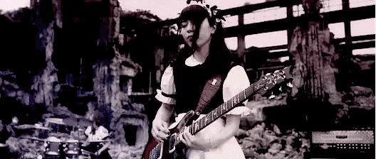 a woman in a maid dress is playing a guitar on a stage .