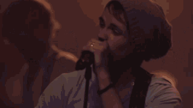 a man playing a guitar and a woman singing into microphones on a stage