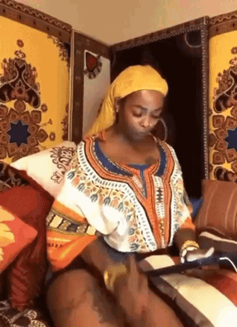 a woman wearing a turban is sitting on a couch with a tablet