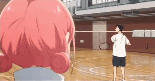 a man and a woman are playing badminton on a court .