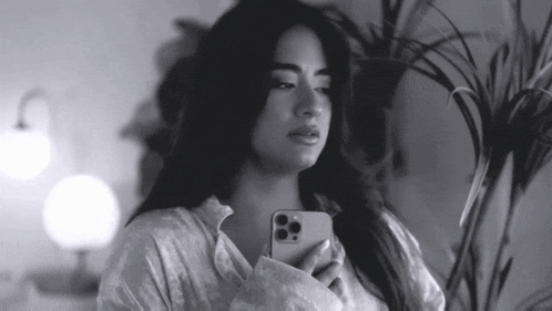 a black and white photo of a woman holding her phone