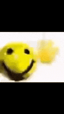 a yellow smiley face is sitting next to a glass of orange juice on a white surface .