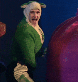 a man in a green sheep costume is laughing