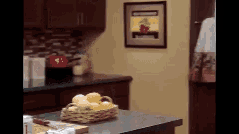 a basket of lemons sits on a counter in a kitchen