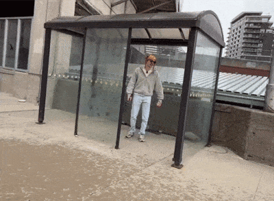 a man standing in front of a glass shelter that says ' trolley ' on it