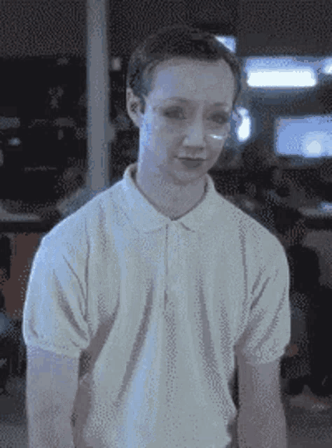 a man wearing a white polo shirt and glasses is standing in a room .