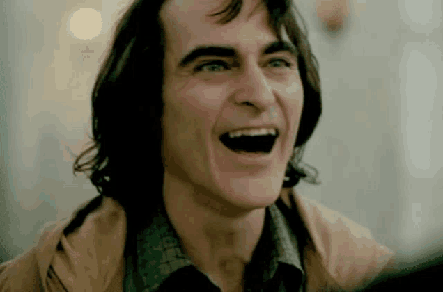a close up of a man laughing with his mouth open and his eyes closed .