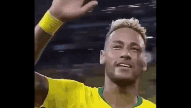 a soccer player in a yellow shirt is waving at the camera .