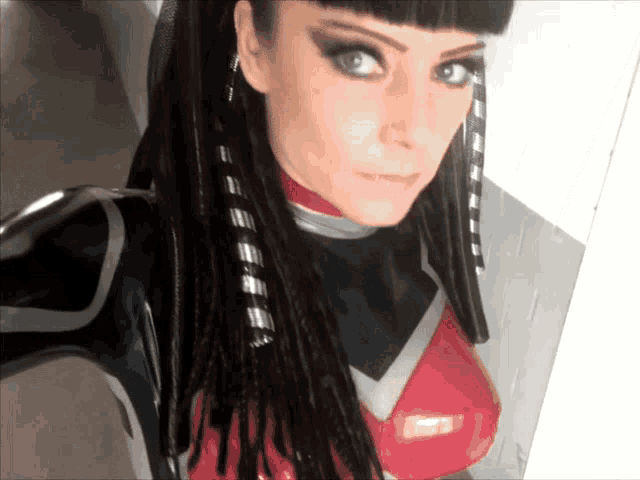a woman with dreadlocks is wearing a red and black outfit