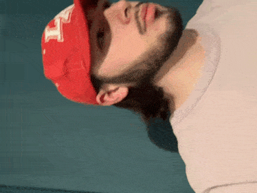 a man with a beard wearing a red hat with the letter h on it