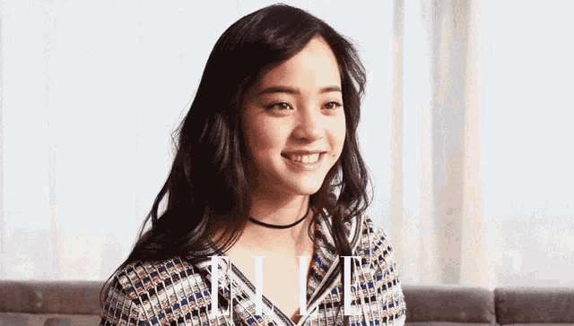 a woman wearing a choker is smiling in front of elle