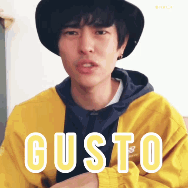 a man wearing a hat and a yellow jacket with the word gusto written on it