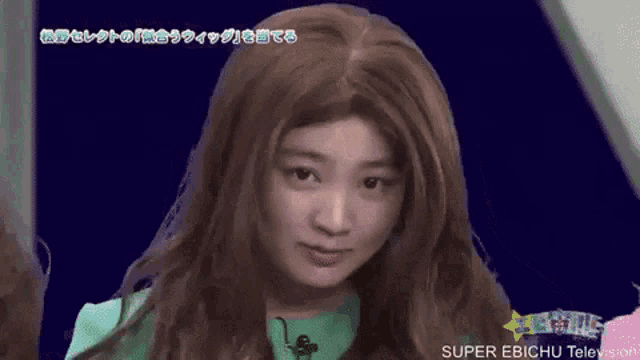 a woman wearing a wig and a green shirt is making a funny face .
