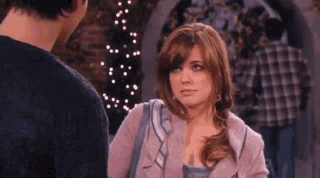 a man and a woman are standing next to each other and the woman is looking at the man .
