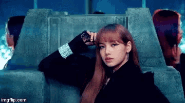 a woman in a black jacket is standing next to a concrete wall .