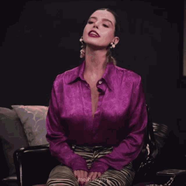 a woman wearing a purple shirt and zebra print pants is sitting in a chair with her eyes closed