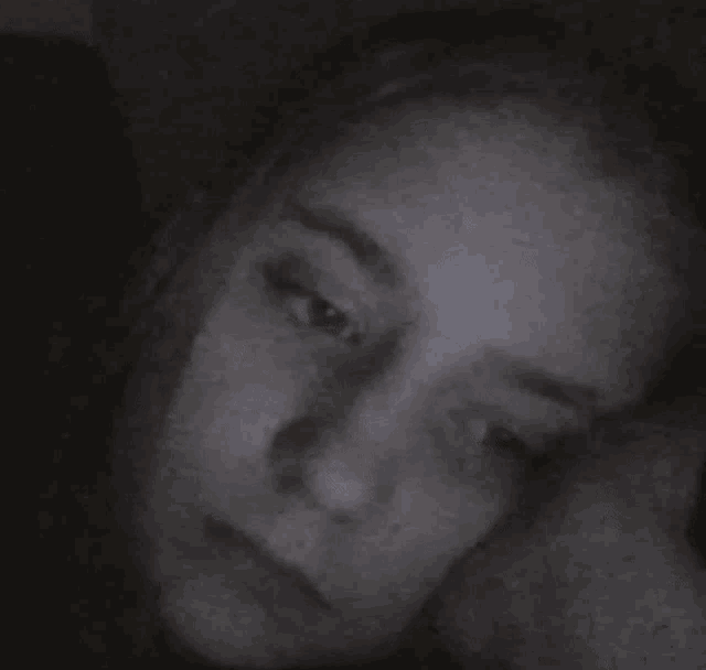 a woman is covering her face with her hand in a black and white photo .