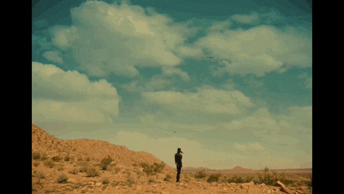 a silhouette of a person standing in front of a large explosion in the sky