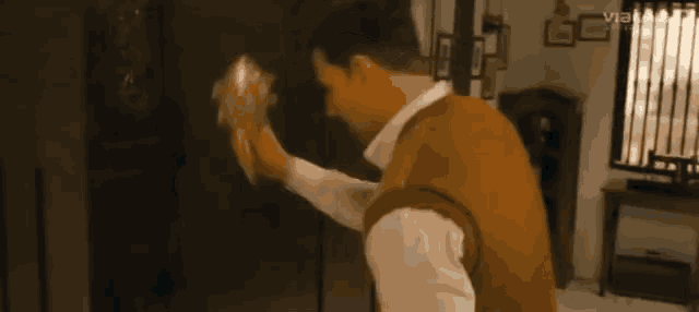 a man in a brown vest is opening a door in a room