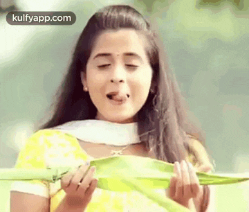 a woman in a yellow dress is holding a green leaf in her hands .