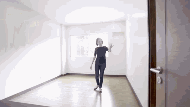 a woman is standing in an empty room with a window and a door .