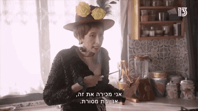 a woman wearing a hat with yellow flowers on it is standing in a kitchen with the number 13 on the bottom right corner