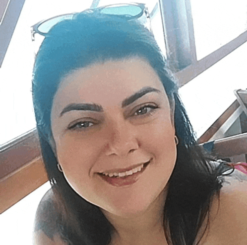 a woman wearing sunglasses is smiling and looking at the camera