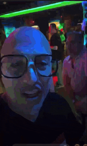 a man wearing glasses is taking a selfie in a dark room
