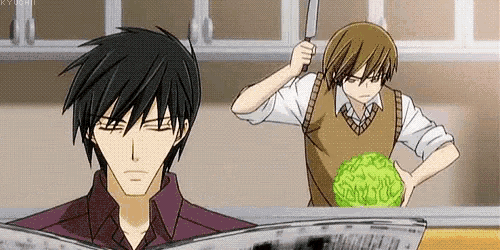 a man is reading a newspaper while another man is holding a knife and cutting a cabbage .