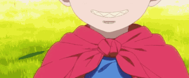 a little girl wearing a red cape and a blue shirt is smiling .