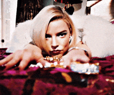 a woman is laying on a bed with her hands on a purse