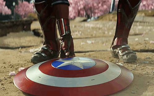 a person standing next to a captain america shield on the ground