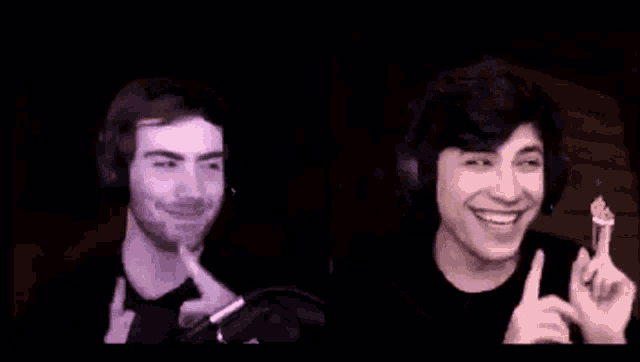 two young men wearing headphones are smiling and pointing at each other .