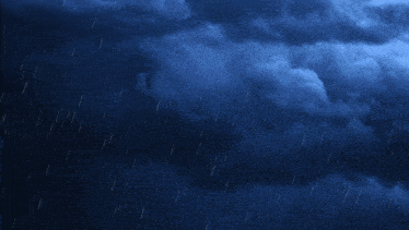 a dark blue sky with a few clouds and rain falling