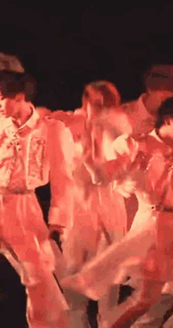 a group of people are dancing on a stage with red lights .