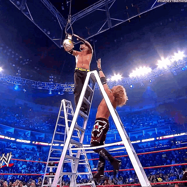 a wrestler is standing on a ladder holding a rope