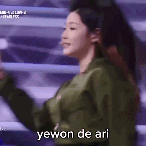 a woman in a green jacket says yewon de ari in a blurry photo
