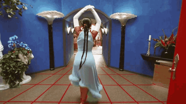 a woman in a blue dress stands in a hallway
