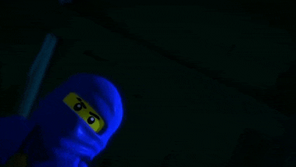 a lego ninjago character is standing in the dark with a sword .