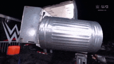 a large trash can is sitting in front of a truck with the letter w on it .