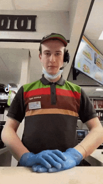 a man wearing a mask and gloves is standing in front of a burger king counter