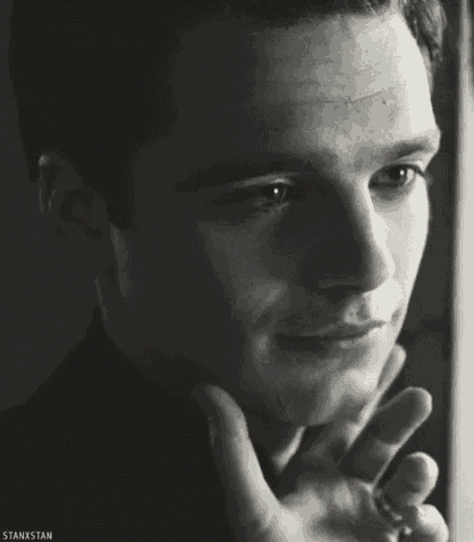 a black and white photo of a man 's face with his hand on his chin .