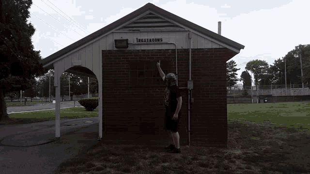 a man stands in front of a building that says restrooms on it