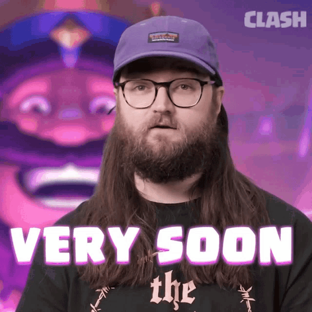 a man with long hair and a beard is wearing a very soon shirt