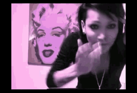 a woman is giving a middle finger in front of a painting of marilyn monroe .