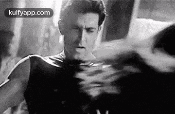 a black and white photo of a man in a superhero costume standing in front of a mirror .