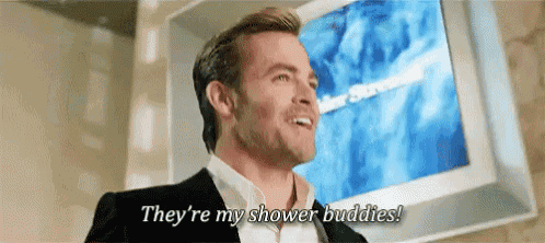 a man in a suit is standing in front of a television and says they 're my shower buddies !